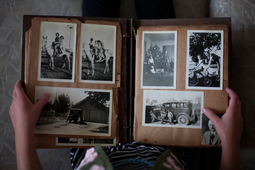 Woman opening an old photo album filled with grayscale family photos