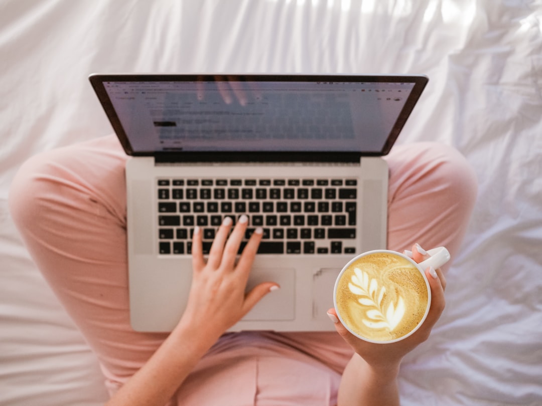 Woman working on a laptop with a cup of coffee at a cozy wooden café table